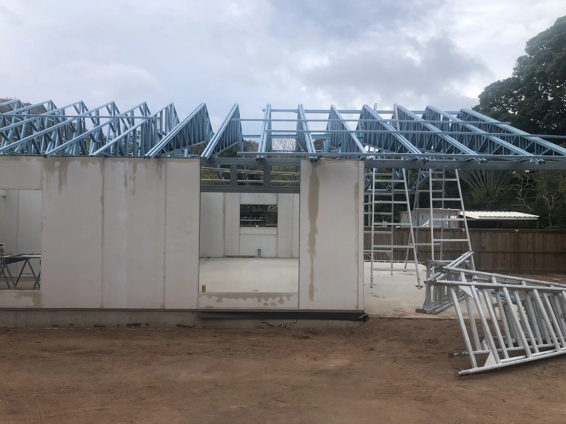 Erected panel walls and stacked roof trusses on a cleared site